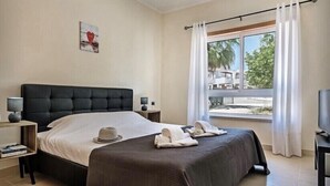 Una habitación de hotel con una cama grande, televisión y ventana con cortinas.