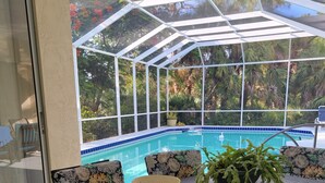 A dining area with a table, chairs, and a view of a pool through a glass enclosure. - Beautiful home on an 18 holes golf course (Sarasota)