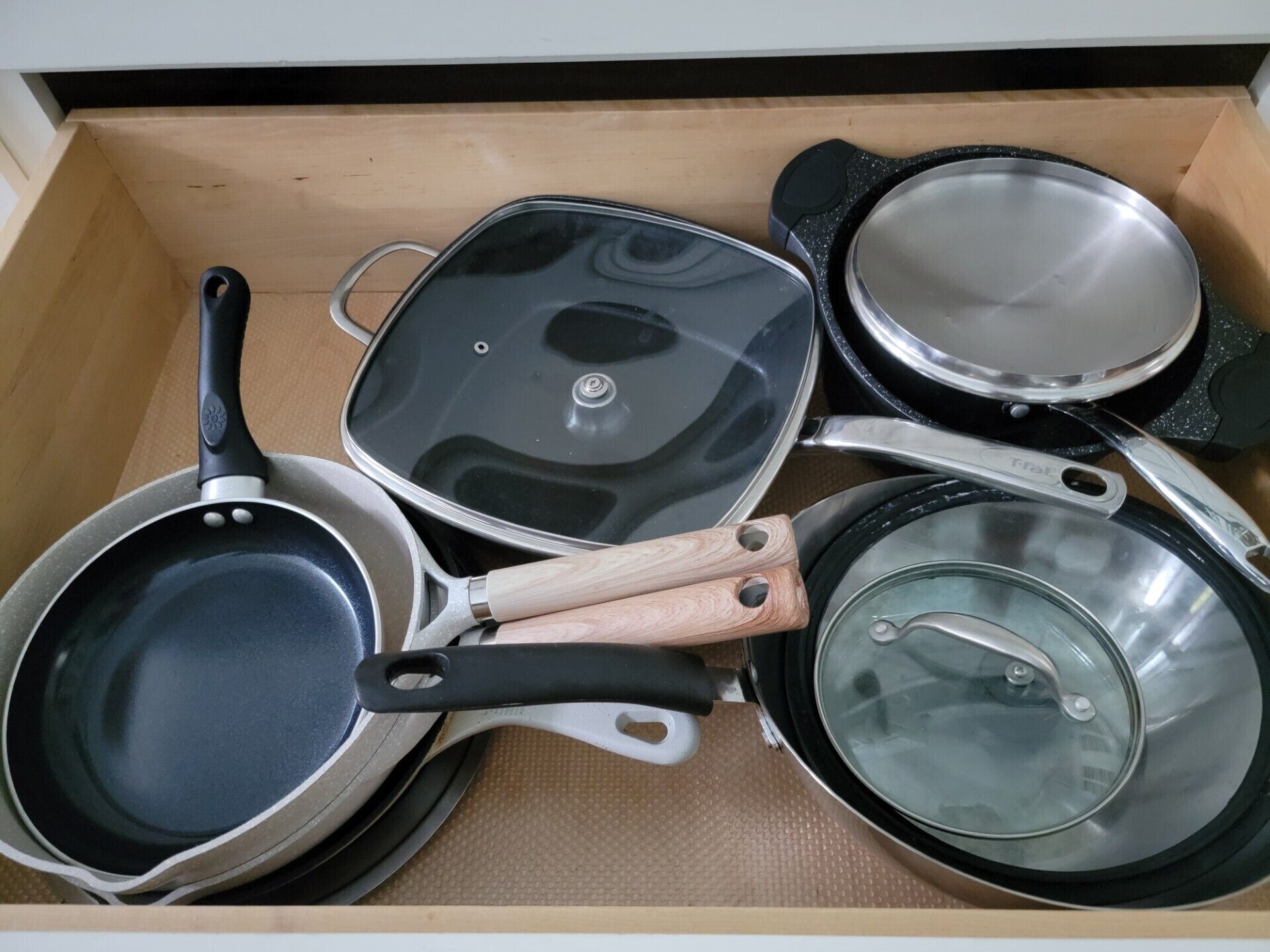 A drawer containing various kitchenware including pots and pans.