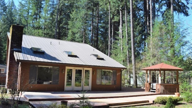 A modern house with a metal roof, large windows, and a wooden deck. - Hopes Cabin (Packwood)