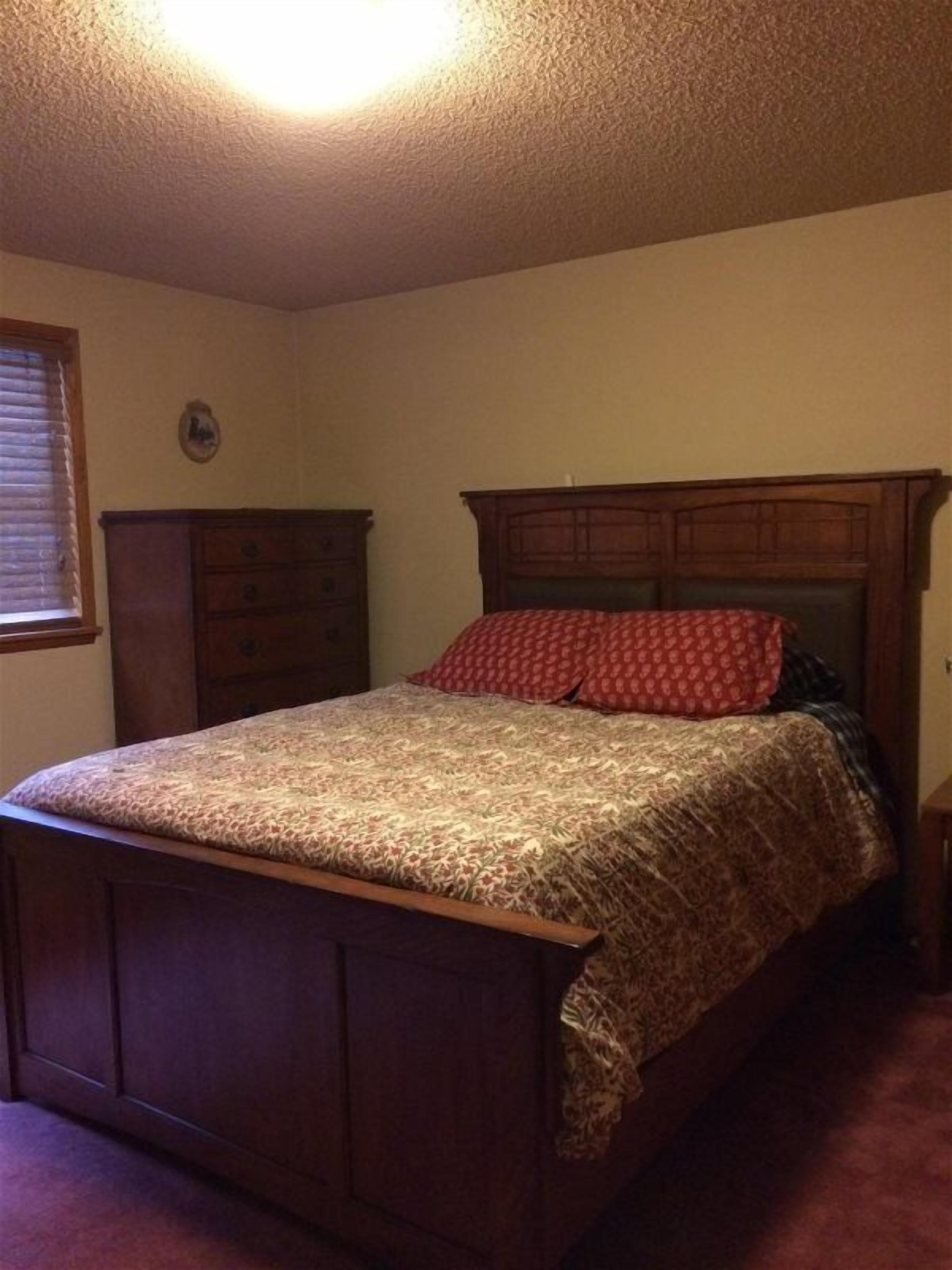 A bedroom with a wooden bed, a dresser, and a nightstand.