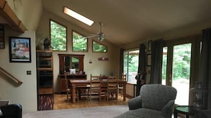 A spacious living room with a large window, a dining area, and a kitchen. - Hopes Cabin (Packwood)