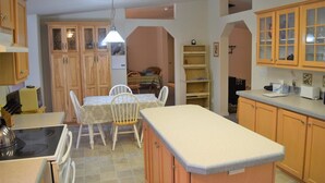A kitchen with wooden cabinets, a dining table with chairs, a stove, and a small island with a countertop. - Rustic Rapids (Packwood)