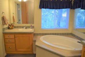 Un ba ño con tocador, bañera y ventana con persianas.
