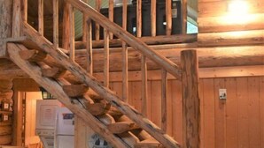 A wooden staircase with a rustic design, a chair, and a small table in a cabin-like interior. - Cascade Log Cabin (Packwood)