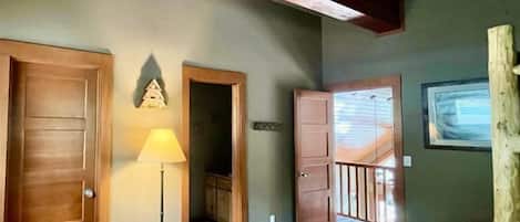 Amplia habitación con techo alto, puertas de madera, una lámpara y vista a un balcón.