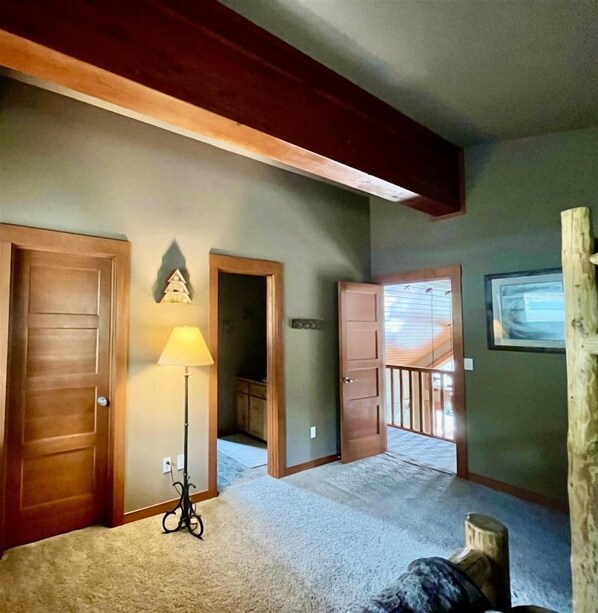 Ruime kamer met een hoge plafond, houten deuren, een lamp en uitzicht op een balkon.
