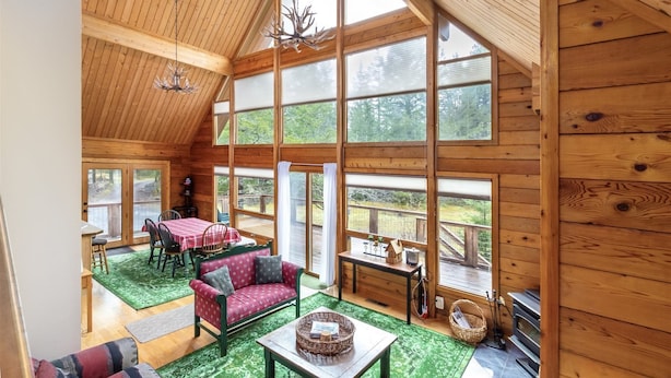 A spacious cabin with a high ceiling, large windows, a dining area, and a cozy seating area. - Trails End (Packwood)
