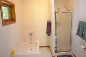 A bathroom with a bathtub, a shower, and a window. - Trails End (Packwood)