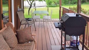 Une terrasse extérieure couverte, avec un banc en bois, un barbecue et une table avec des chaises.