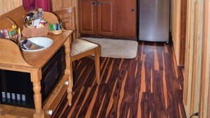 Une cuisine de taille réduite, dotée de meubles de rangement en bois, d’un four à micro-ondes, d’un évier et d’un réfrigérateur.