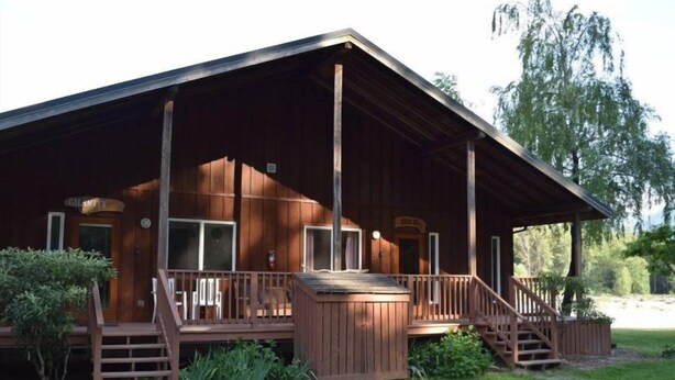 Une cabane en bois avec une véranda, un petit escalier et un espace abrité.