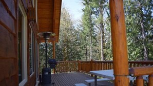 A wooden deck with a table and benches, surrounded by trees. - Creekside Cabin (Packwood)