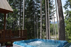 A hot tub surrounded by tall trees, a wooden deck, and a small pavilion. - Antler Ridge (Packwood)