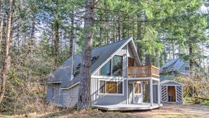 A two-story cabin with a balcony, surrounded by dense forest. - Lake Creek Cabin (Packwood)