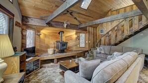 A cozy cabin interior with a wooden interior, a fireplace, a sofa, and a staircase. - Lake Creek Cabin (Packwood)