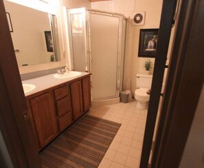 A bathroom with a wooden vanity, a shower, and a toilet.