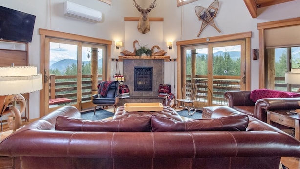 A spacious living room with leather sofas, a fireplace, and a mounted deer head. - Ravenwood (Packwood)