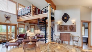 A spacious living area with a loft bedroom, a wooden staircase, and a dining table. - Ravenwood (Packwood)