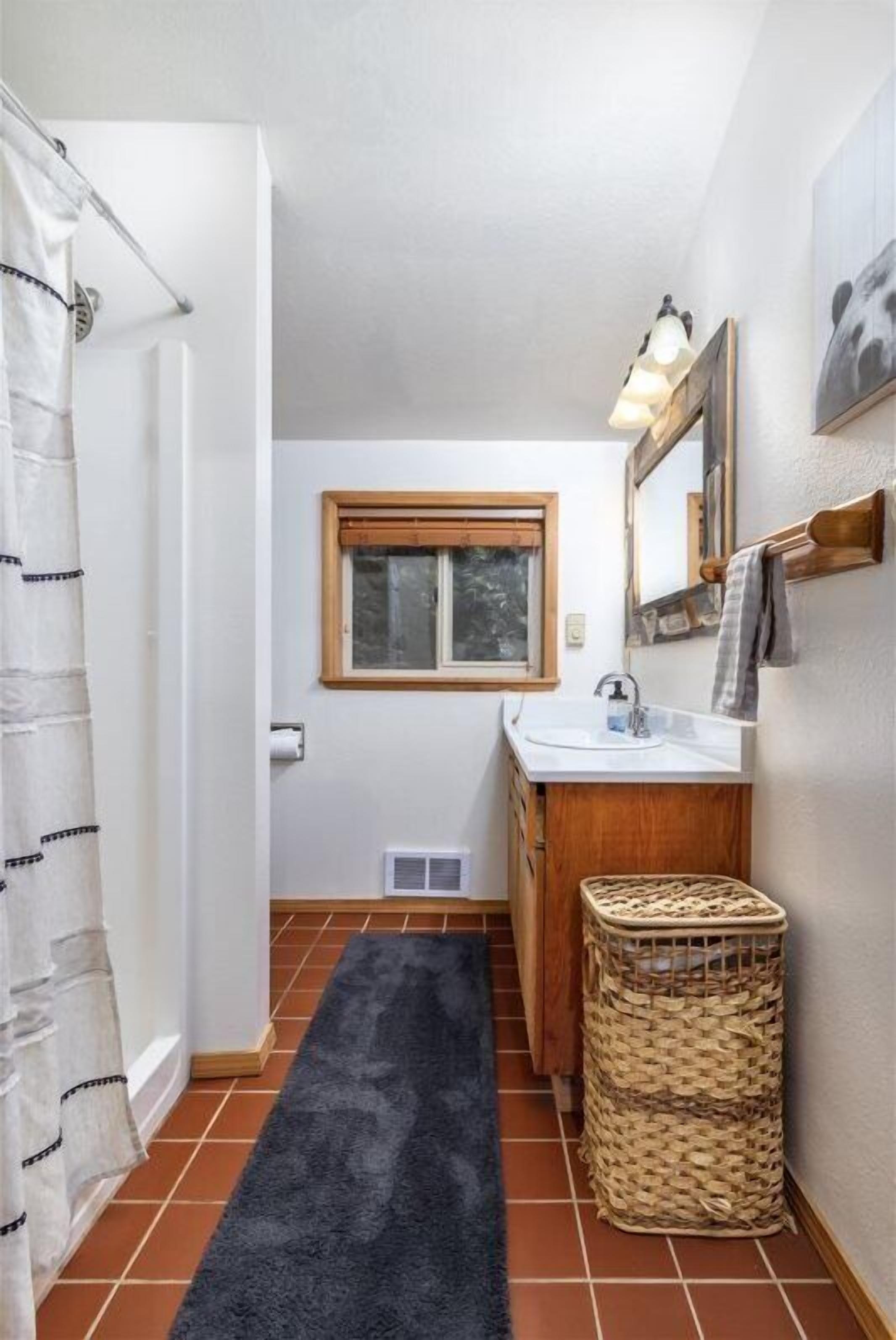 Une salle de bain avec une fenêtre, un lavabo, un miroir et un porte-serviettes.