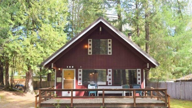 A cabin with a wooden deck, a covered porch, and a small outdoor seating area.