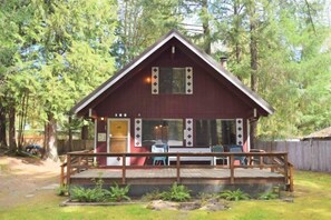 Een chalet met een houten terras, een overdekte veranda en een klein zitgedeelte buiten.