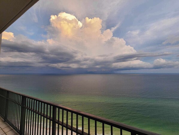 A balcony with a view of the ocean and a cloudy sky.