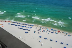 Une plage bordée de rangées de parasols et de chaises de plage.