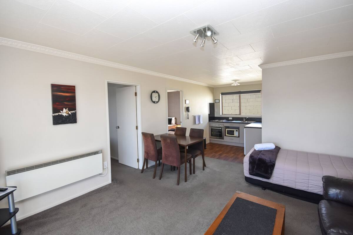 A compact living space with a dining area, kitchenette, and a sofa.