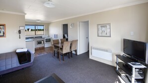 A compact living space with a kitchenette, a dining area, a sofa, and a TV. - ASURE Adrian Motel (Dunedin)