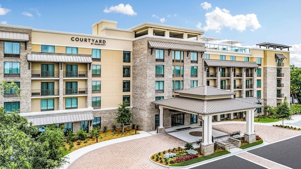 A Courtyard by Marriott hotel with a brick facade, multiple balconies, and a covered entrance area. - Courtyard by Marriott Hilton Head Island (Hilton Head Island)