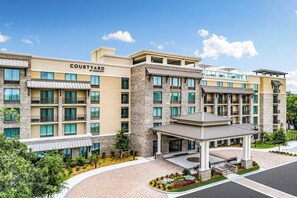 Een Courtyard by Marriott hotel met een bakstenen gevel, meerdere balkons en een overdekte entree.