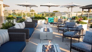A rooftop lounge with outdoor seating, a fire feature, and umbrellas. - Courtyard by Marriott Hilton Head Island (Hilton Head Island)