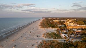 A beach with a long stretch of sand, a few buildings, and a clear sky. - Courtyard by Marriott Hilton Head Island (Hilton Head Island)
