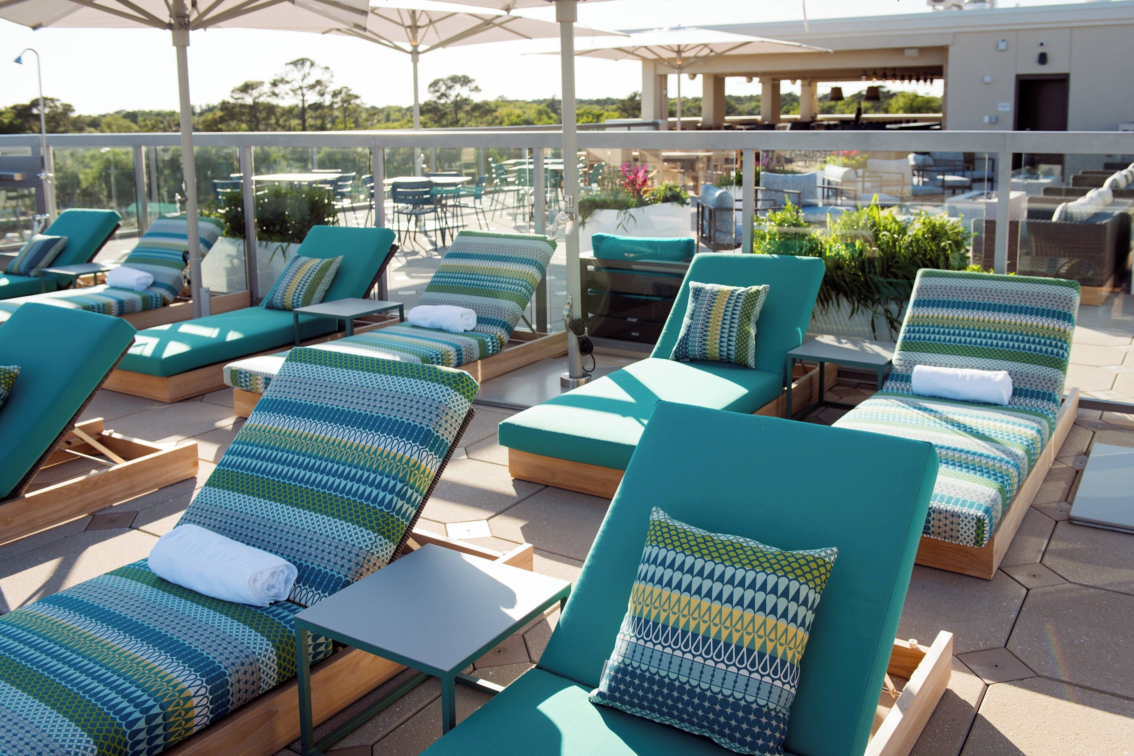 Uma área de lounge no terraço com várias cadeiras e mesas, algumas com toalhas.