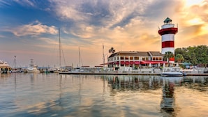 A waterfront property with a prominent lighthouse, marina with boats, and a building with red awnings. - Courtyard by Marriott Hilton Head Island (Hilton Head Island)
