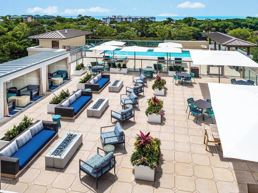 A rooftop patio with outdoor seating, a pool, and a view of the ocean.