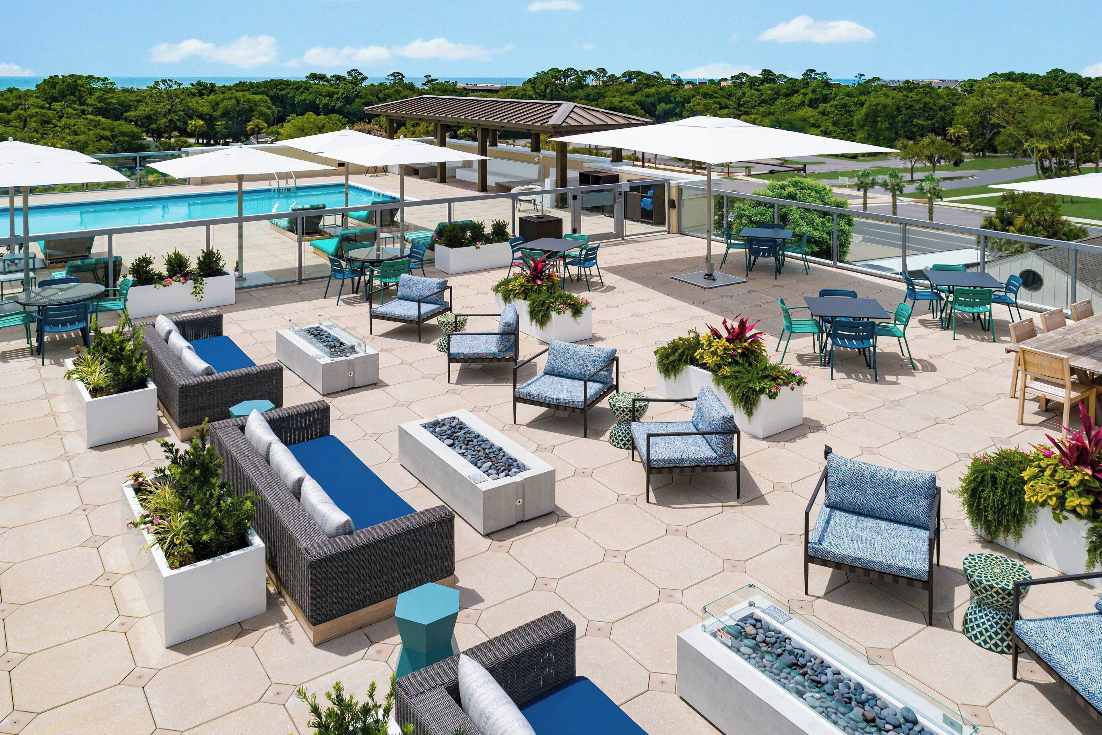 A rooftop patio area with outdoor seating, a pool, and a view of the surrounding landscape.