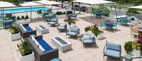 A rooftop patio area with outdoor seating, a pool, and a view of the surrounding landscape.