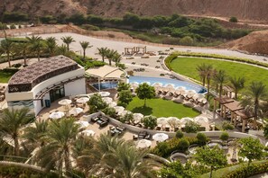 A resort with a pool, outdoor seating, and palm trees.