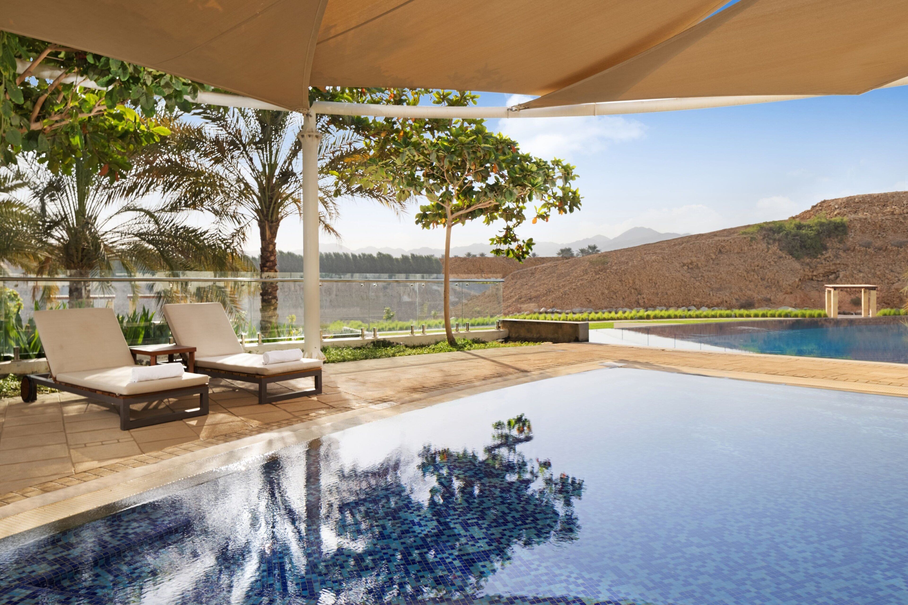 Una piscina infinita con sillones de descanso y vistas a un paisaje montañoso.