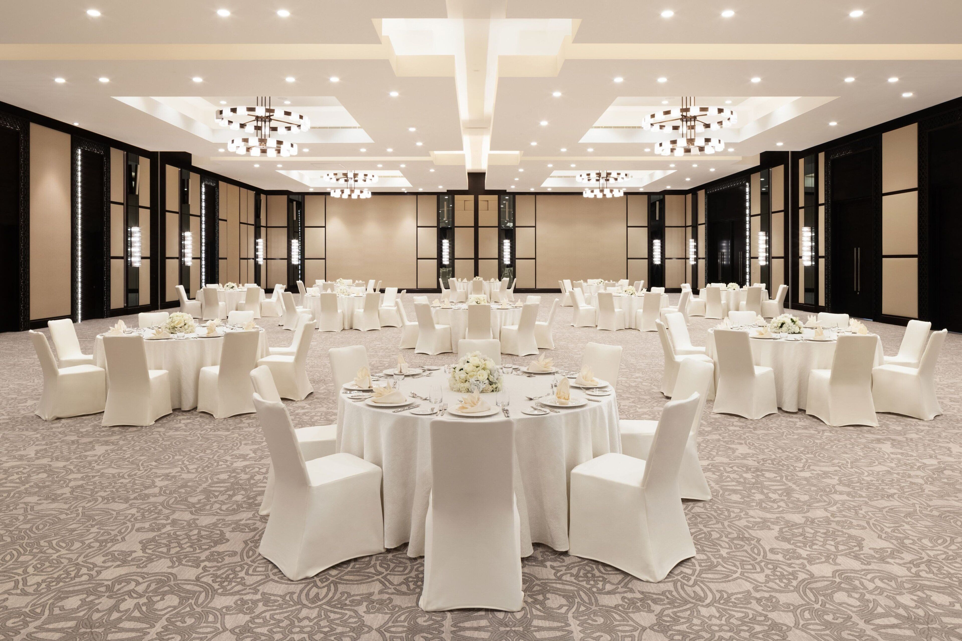 A large, well-lit conference room with round tables and white chairs, arranged for a formal event.