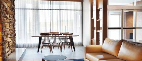 Una sala moderna con un sofá de cuero, una mesa de comedor con sillas y una pared de acento de piedra.