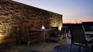 An outdoor patio with stone walls, a fire feature, and seating. - Fairfield Inn & Suites by Marriott Sheboygan (Sheboygan)