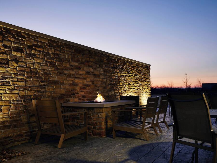 An outdoor patio with stone walls, a fire feature, and seating.