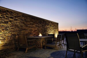 Un patio al aire libre con paredes de piedra, una chimenea y asientos.