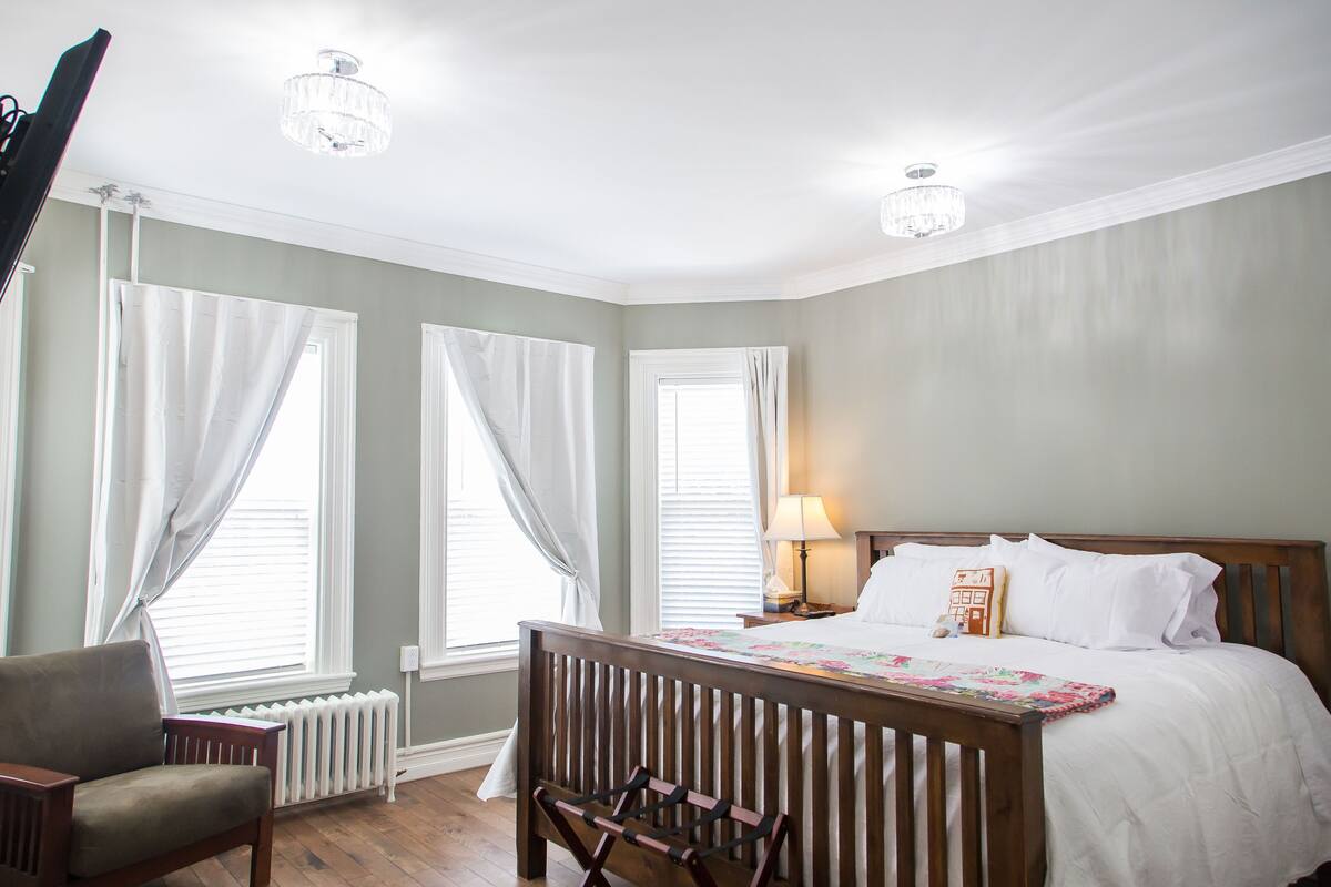 A bedroom with a wooden bed, a nightstand, a lamp, and a chair.