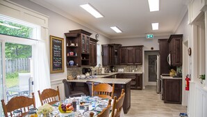 Cuina amb armaris de fusta fosca, una illa central i taula de dinar per a sis.