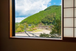 A view through a window of a mountainous landscape with a bridge and a building.