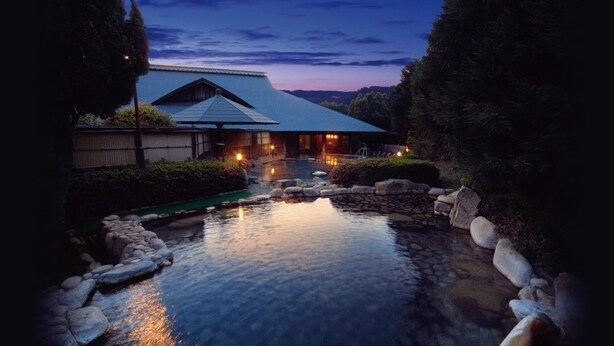 Un ryokan japonés tradicional con un estanque de carpas koi y una valla de madera.